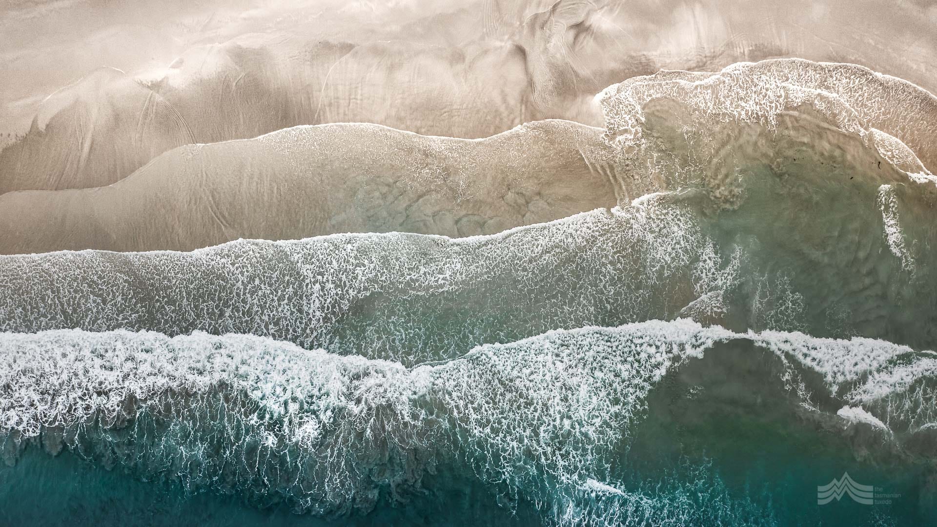 Aerial photo of patterns of sand and waves at the oceans edge